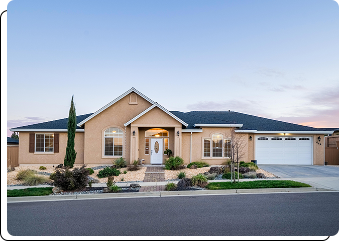 A house with a driveway and bushes in front of it